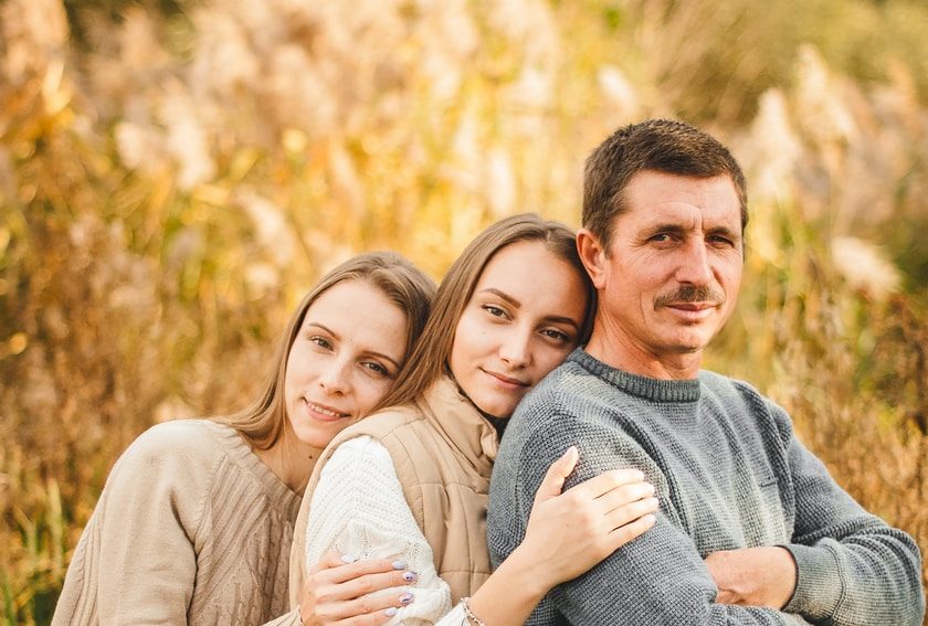 man in gray sweater hugging woman in gray sweater